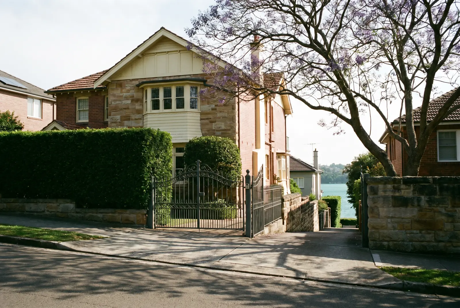 A heritage home behind a clipped hedge and iron gates in Bellevue Hill